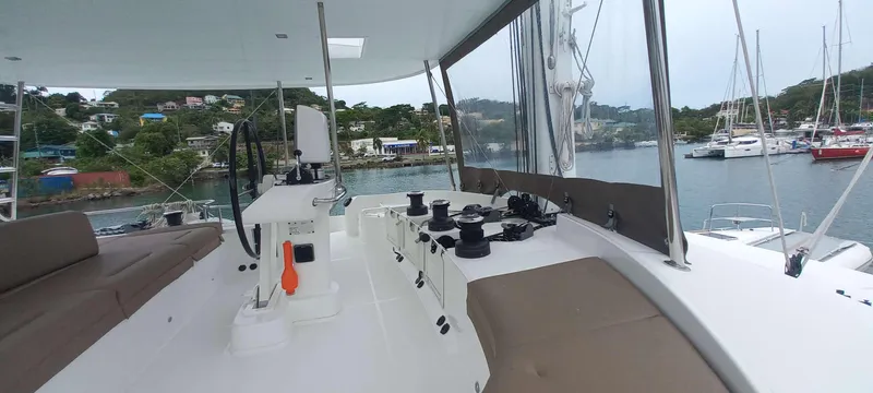 Amea Yacht Photos Pics 2014 Lagoon 52 F catamaran deck with seating, steering wheel, and marina view.