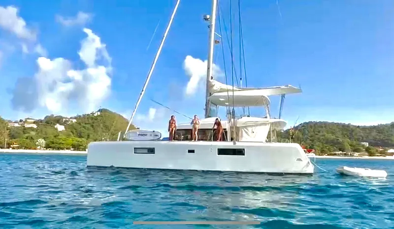 Amea Yacht Photos Pics 2014 Lagoon 52 F catamaran sailing near a tropical coastline with clear blue skies.