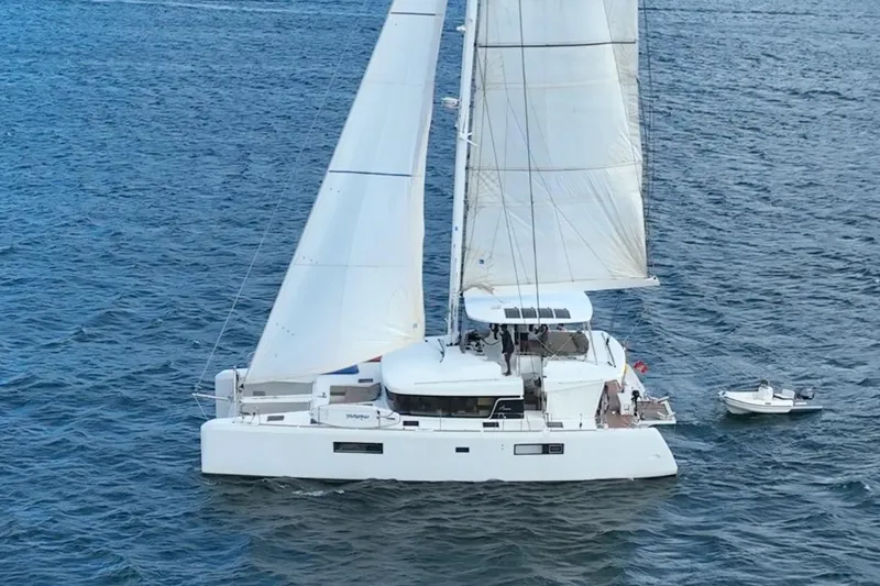Amea Yacht Photos Pics 2014 Lagoon 52 F catamaran sailing on open water with dinghy attached.