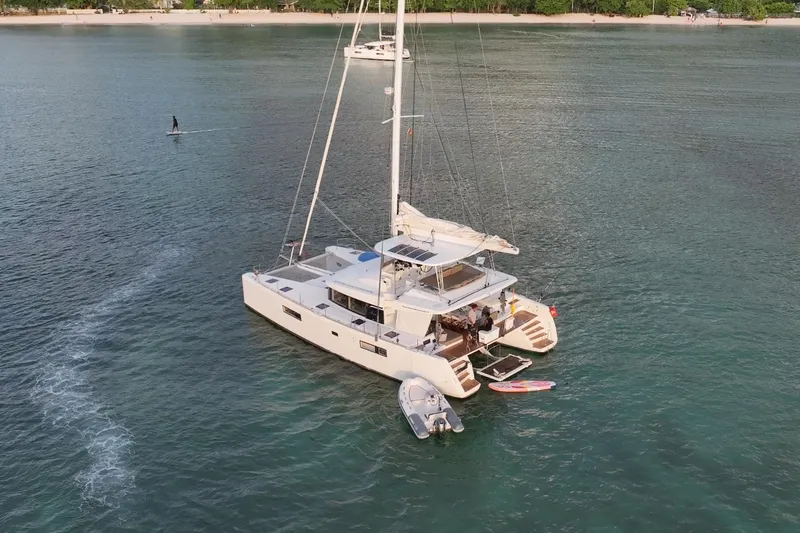 Amea Yacht Photos Pics Aerial view of 2014 Lagoon 52 F catamaran anchored near a beach.