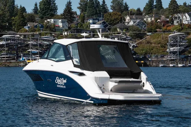  Yacht Photos Pics 2023 Sea Ray Sundancer 320 Coupe on water, with scenic shoreline background.