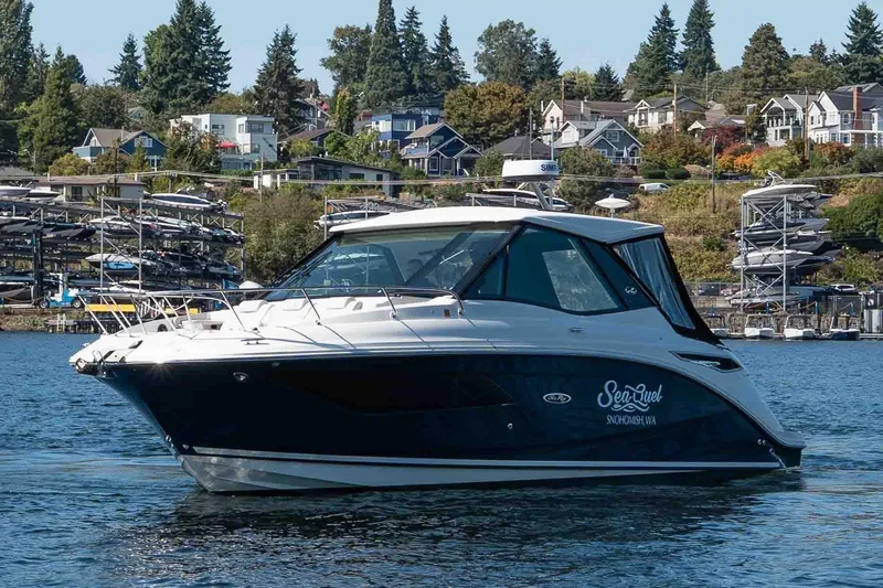  Yacht Photos Pics 2023 Sea Ray Sundancer 320 Coupe on a scenic waterfront with houses in the background.