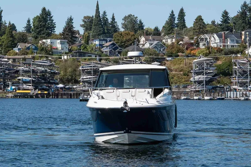  Yacht Photos Pics 2023 Sea Ray Sundancer 320 Coupe on water, with marina and houses in background.