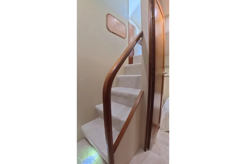 Never Been Fished Yacht Photos Pics Staircase inside 2002 Ocean Yachts 52 SS, featuring wooden handrail and carpeted steps.