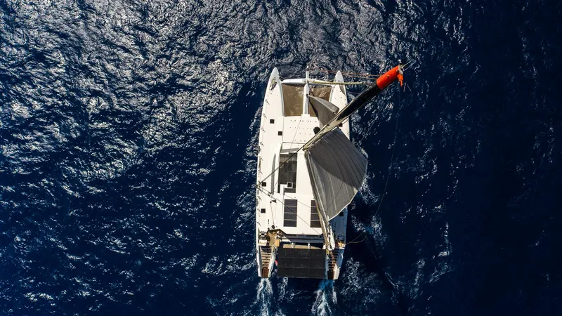 Orion Yacht Photos Pics Aerial view of 2008 Catana 90 catamaran sailing on deep blue ocean.