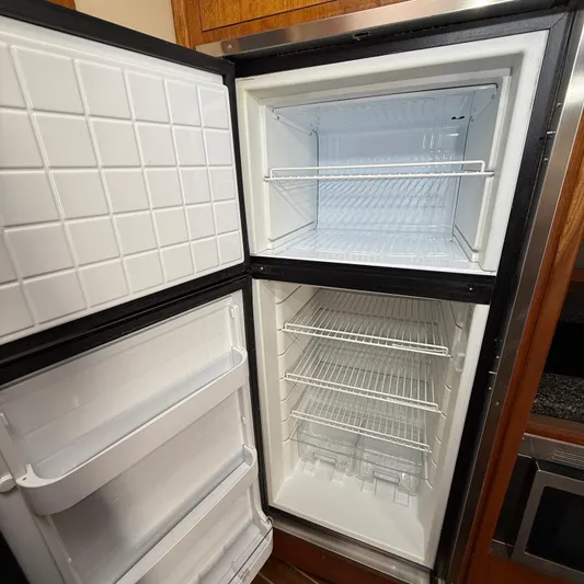  Yacht Photos Pics Open refrigerator and freezer inside 2006 Cruisers Yachts 420 Express, showcasing spacious interior.