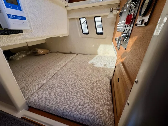  Yacht Photos Pics 2024 Ranger Tugs R-27 cabin interior with cushioned bed and control panel.