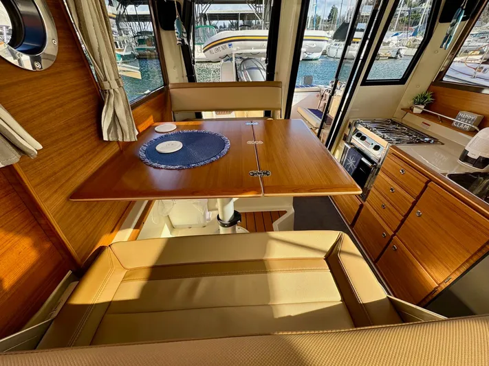  Yacht Photos Pics 2024 Ranger Tugs R-27 interior with dining area, wooden cabinetry, and marina view.