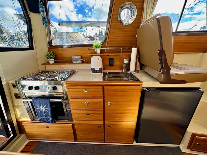  Yacht Photos Pics 2024 Ranger Tugs R-27 interior kitchen with stove, sink, and refrigerator.