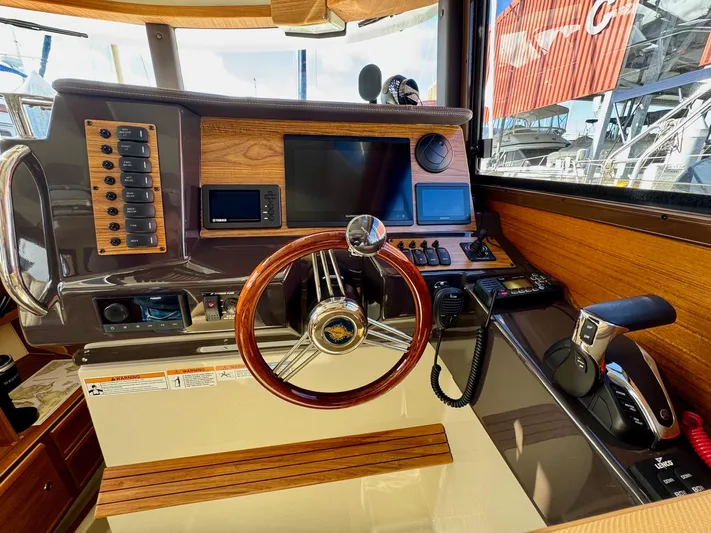  Yacht Photos Pics 2024 Ranger Tugs R-27 helm with wooden steering wheel and modern navigation controls.