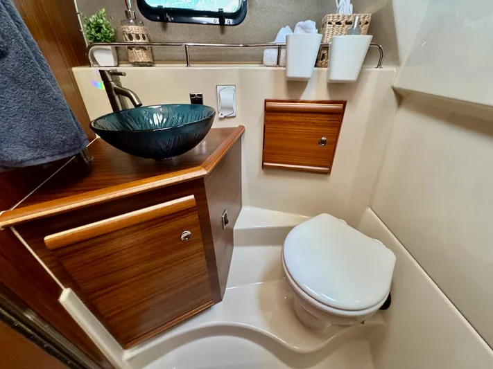  Yacht Photos Pics 2024 Ranger Tugs R-27 bathroom with modern sink, wooden cabinetry, and compact toilet.