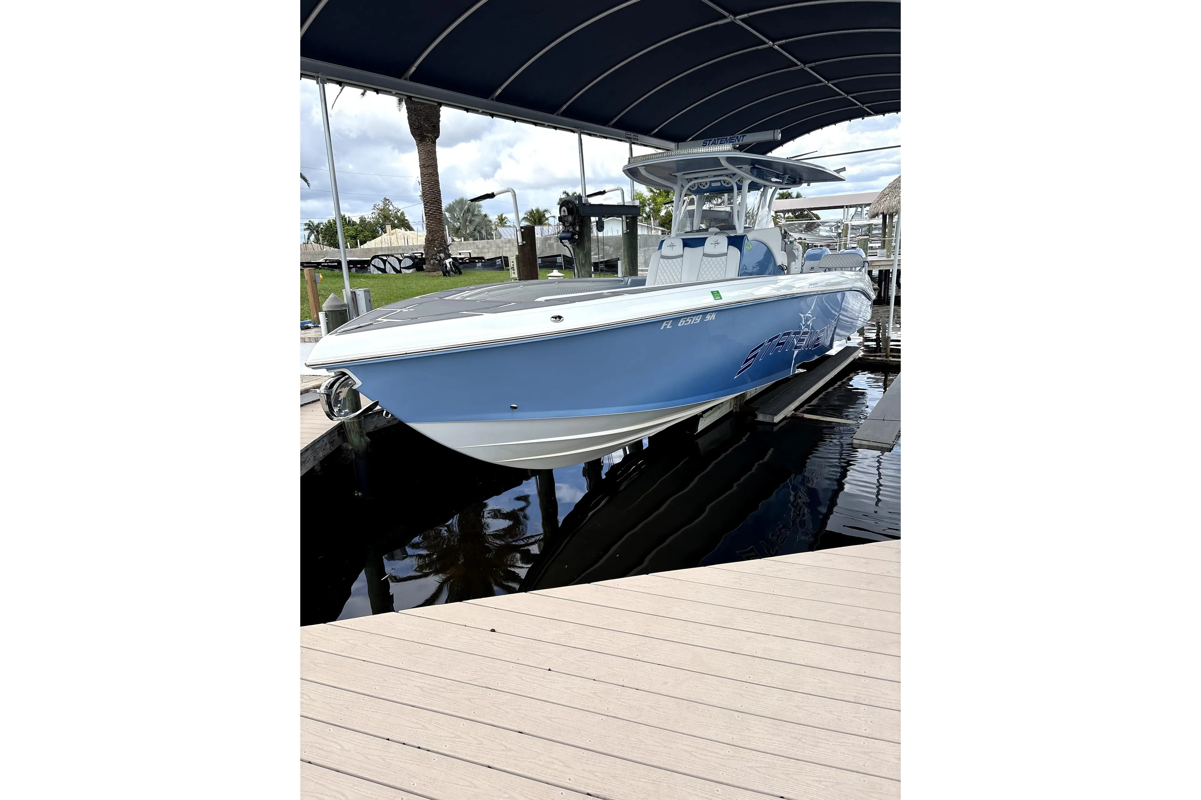 Blue 2019 Statement Fishing Edition boat docked under a canopy.