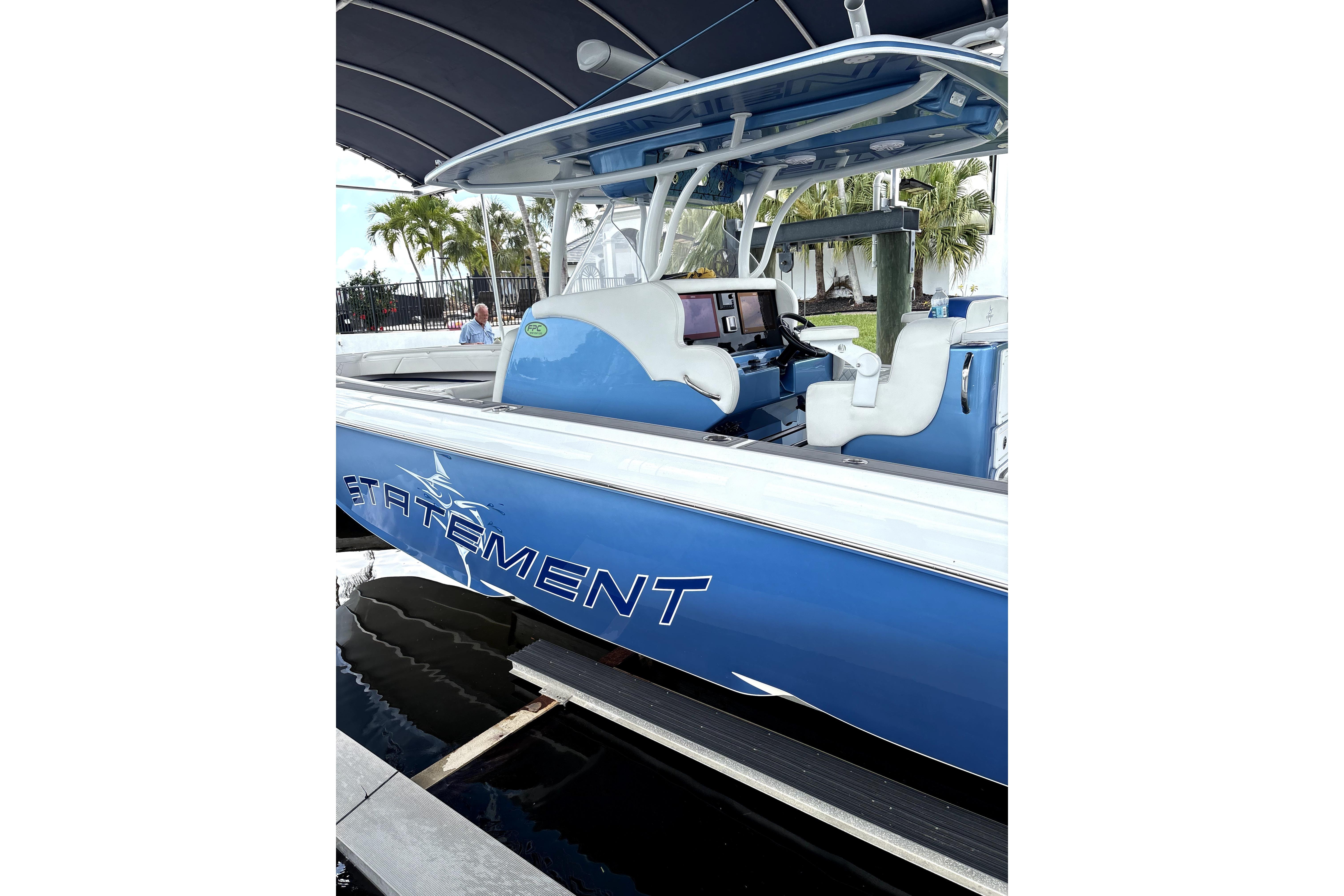 2019 Statement Fishing Edition boat, blue exterior, docked under canopy, with white seating.