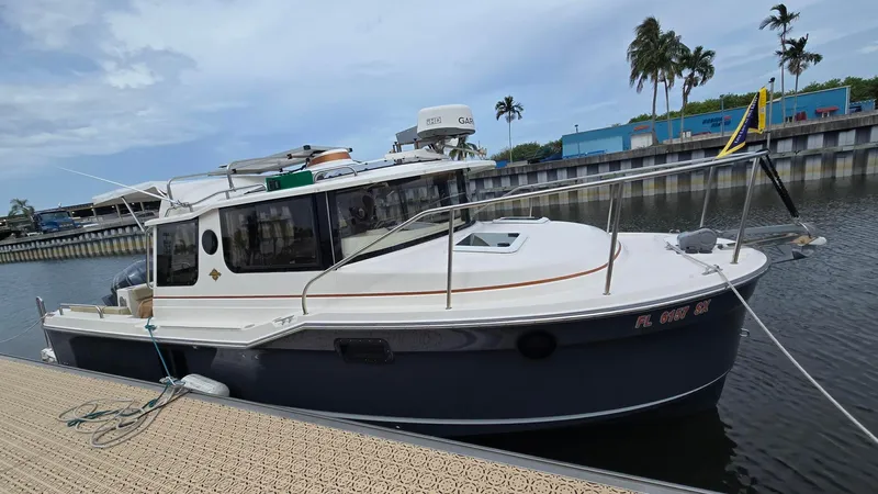  Yacht Photos Pics 2021 Ranger Tugs R-25 boat docked in a marina with palm trees in the background.