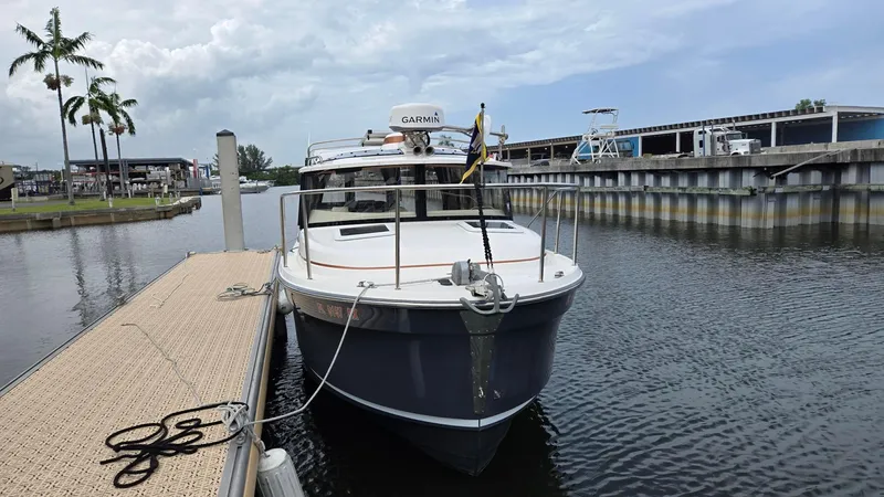  Yacht Photos Pics 2021 Ranger Tugs R-25 docked at marina with palm trees and cloudy sky.