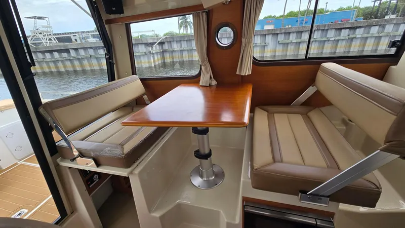  Yacht Photos Pics Interior of 2021 Ranger Tugs R-25 with seating and wooden table by a window.