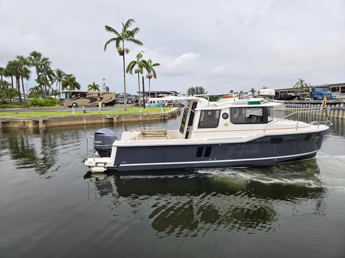  Yacht Photos Pics 2021 Ranger Tugs R-25 boat cruising in a marina with palm trees in the background.