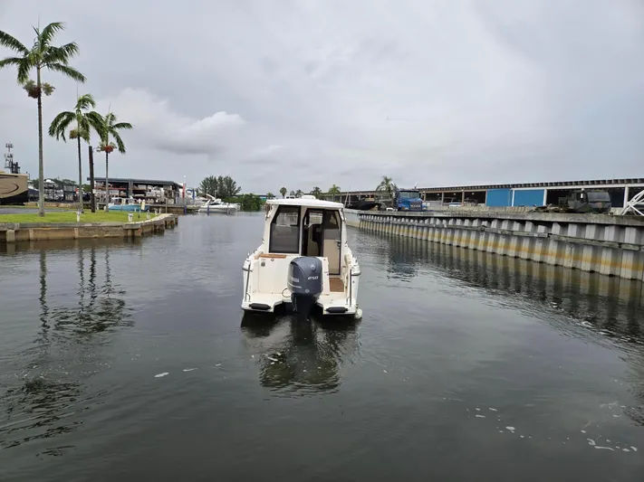  Yacht Photos Pics 2021 Ranger Tugs R-25 boat navigating a calm canal with palm trees and docks.