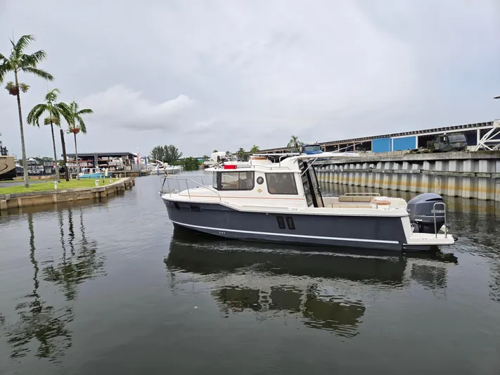  Yacht Photos Pics 2021 Ranger Tugs R-25 boat docked in a marina with palm trees and overcast sky.