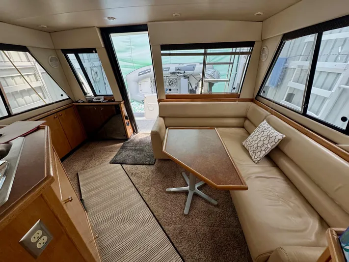 The Journey Yacht Photos Pics 1999 Bayliner 3988 Command Bridge Motoryacht interior with beige seating and wooden table.