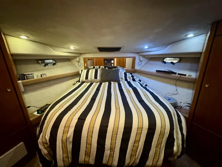 The Journey Yacht Photos Pics 1999 Bayliner 3988 Command Bridge Motoryacht bedroom with striped bedding and ambient lighting.