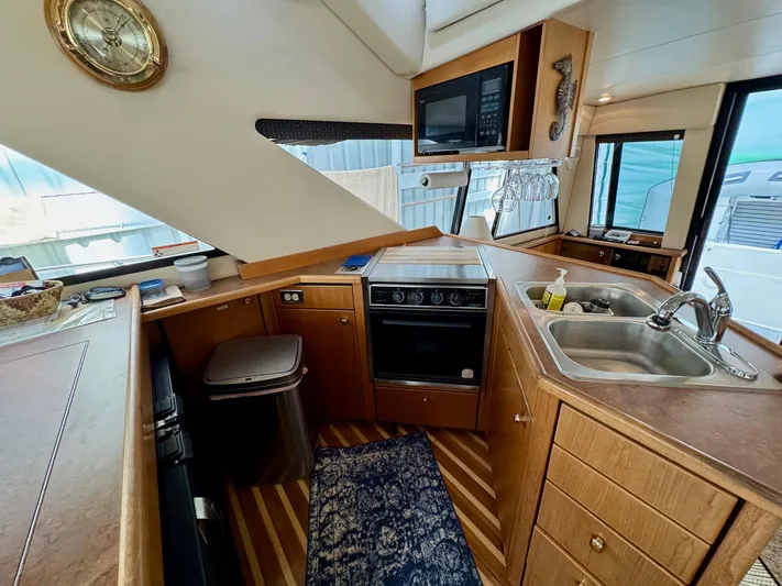 The Journey Yacht Photos Pics 1999 Bayliner 3988 Command Bridge Motoryacht kitchen with stove, sink, and wooden cabinetry.