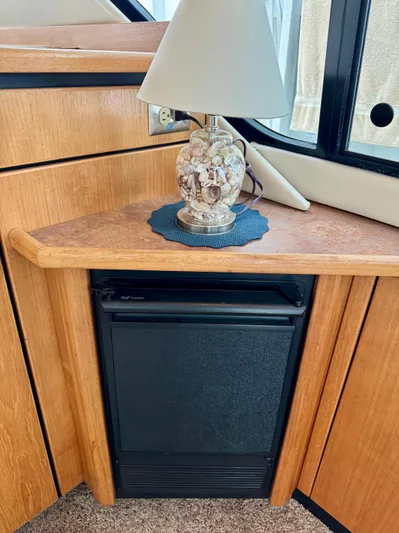 The Journey Yacht Photos Pics 1999 Bayliner 3988 yacht interior with lamp and mini fridge on wooden counter.