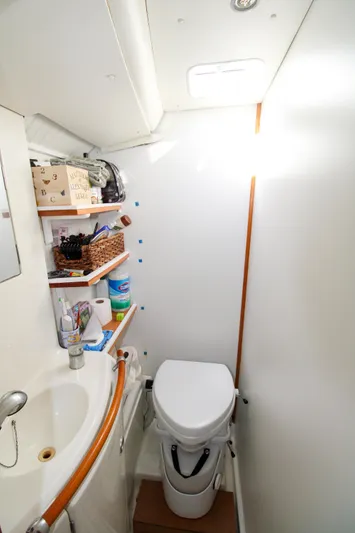 One Life Yacht Photos Pics Compact bathroom in 2002 Lagoon 410 catamaran with sink, toilet, and storage shelves.