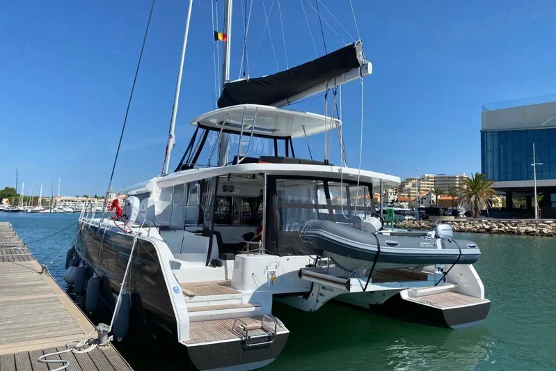 Alegr&iacute;a Yacht Photos Pics 2020 Lagoon 46 catamaran docked at marina, featuring modern design and inflatable dinghy.