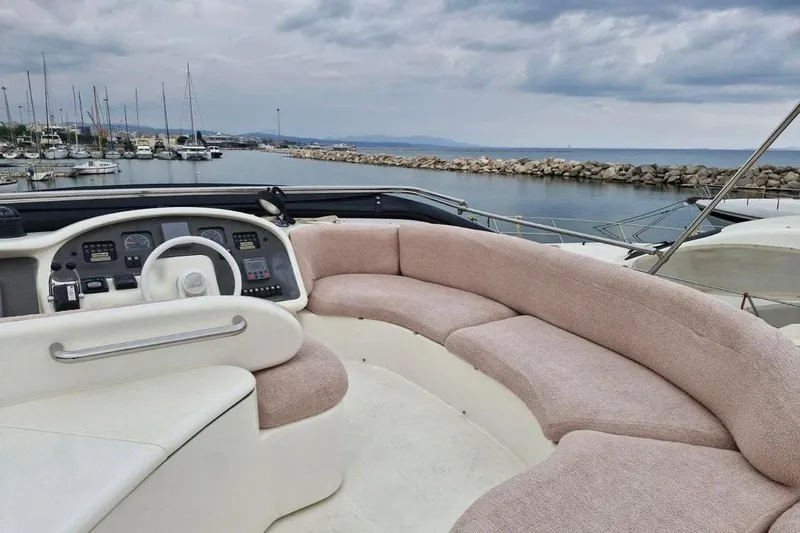 Nina Yacht Photos Pics 2000 Azimut 52 yacht interior with plush seating and control panel, docked at marina.