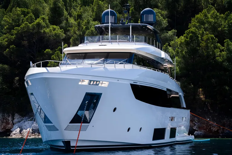 Sk Yacht Photos Pics Luxurious 2019 Custom Line Navetta 33 yacht anchored near lush green forest.
