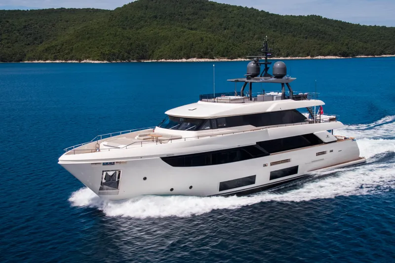 Sk Yacht Photos Pics Luxurious 2019 Custom Line Navetta 33 yacht cruising on blue waters near a lush green island.