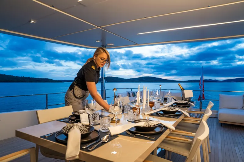 Sk Yacht Photos Pics Crew member setting elegant dining table on 2019 Custom Line Navetta 33 yacht at sunset.