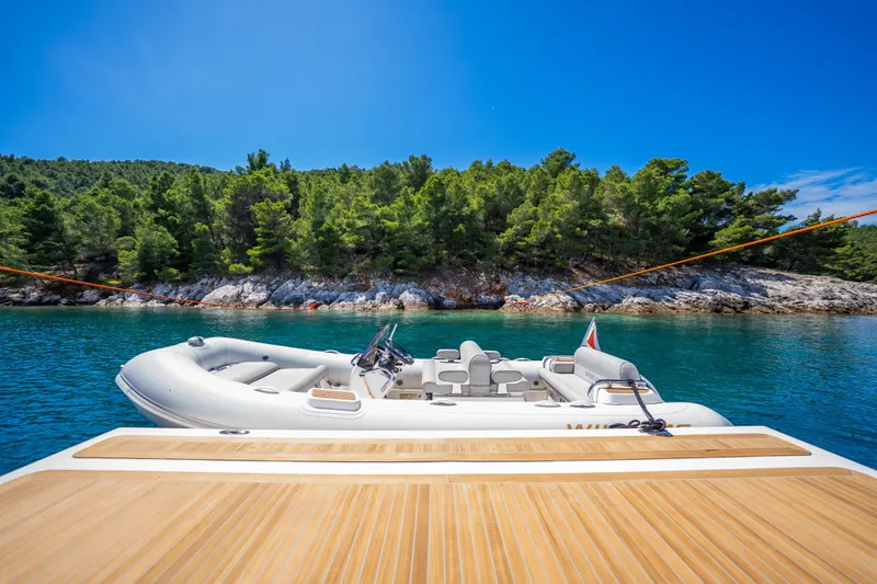 Sk Yacht Photos Pics Luxury yacht Navetta 33 with tender boat, anchored near lush green island, 2019 model.