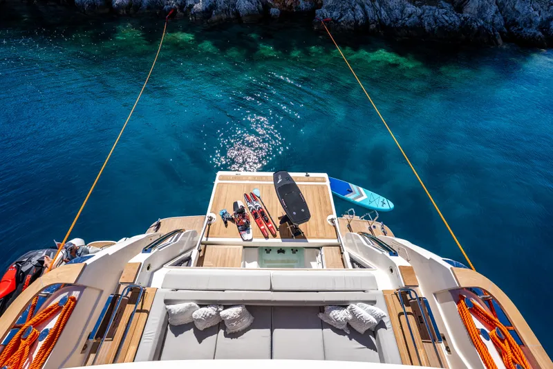 Sk Yacht Photos Pics Luxurious 2019 Custom Line Navetta 33 yacht with water sports gear on deck, anchored in clear blue waters.