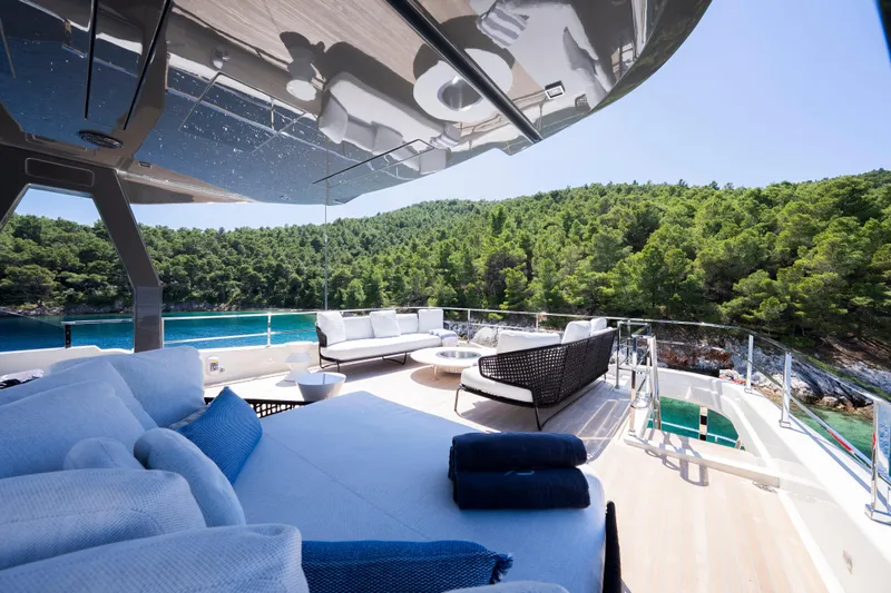 Sk Yacht Photos Pics Luxurious 2019 Custom Line Navetta 33 yacht deck with elegant seating, overlooking serene waters and lush greenery.