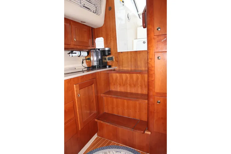 Holly Ann Yacht Photos Pics 2005 Rampage 38 Express interior with wooden cabinetry and stairs, featuring a coffee maker.