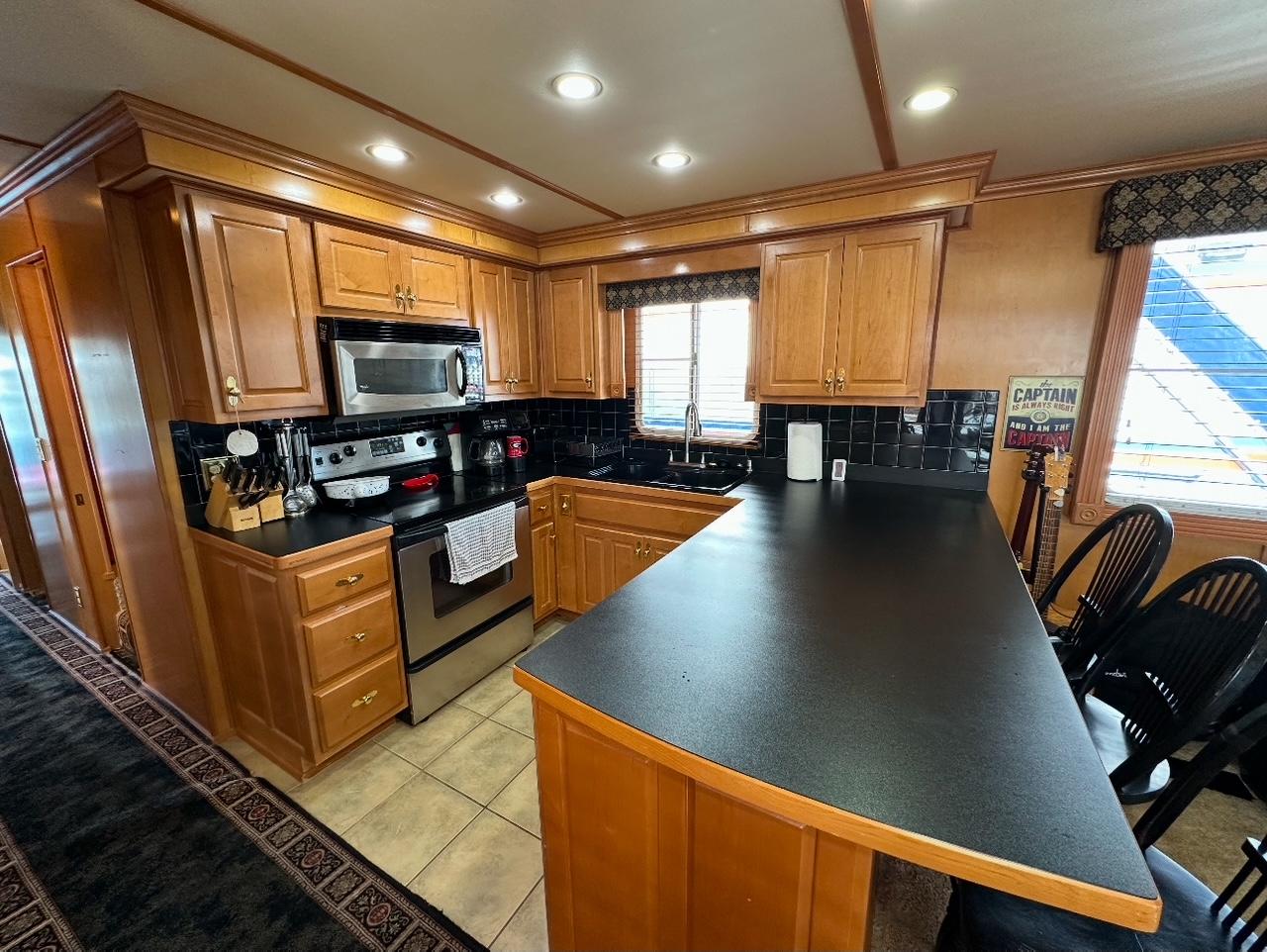 Modern kitchen in a 2006 Lakeview 16x68 houseboat with wooden cabinets and stainless steel appliances.