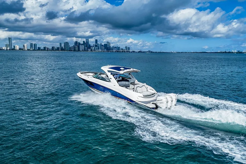 Dock's Knott Inn II Yacht Photos Pics 2018 Sea Ray SLX 350 Outboard cruising on blue ocean with city skyline backdrop.