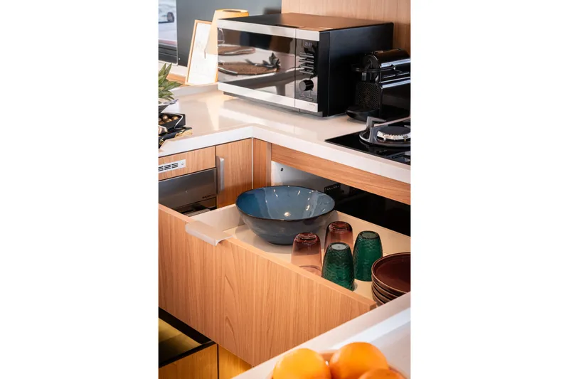  Yacht Photos Pics Modern kitchen with wooden cabinets, microwave, and colorful glassware in a Bali 5.2 model, 2026.