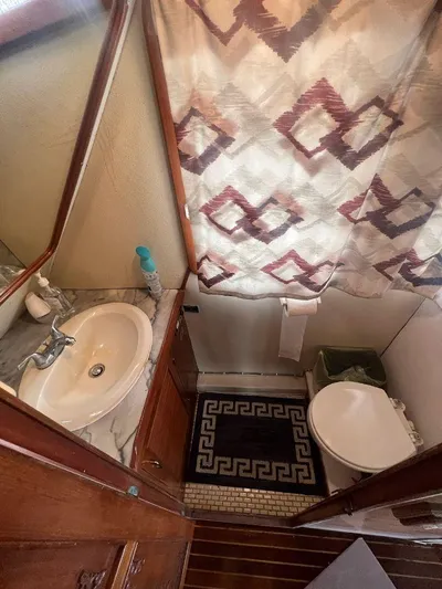 Majestic Yacht Photos Pics Bathroom in a 1987 Marine Trader 62 Med Yacht with sink, toilet, and patterned shower curtain.