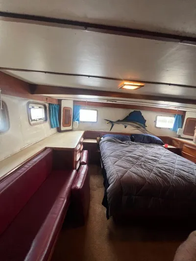 Majestic Yacht Photos Pics 1987 Marine Trader 62 Med Yacht bedroom with bed, seating, and wall-mounted fish decor.