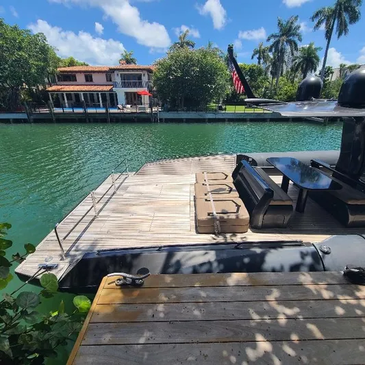  Yacht Photos Pics Luxury Anvera 55 yacht docked by waterfront home, sunny day, palm trees in background.