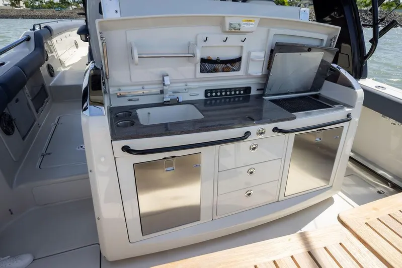 Pachanga Yacht Photos Pics 2021 Boston Whaler 420 Outrage boat kitchen with sink, grill, and storage drawers.
