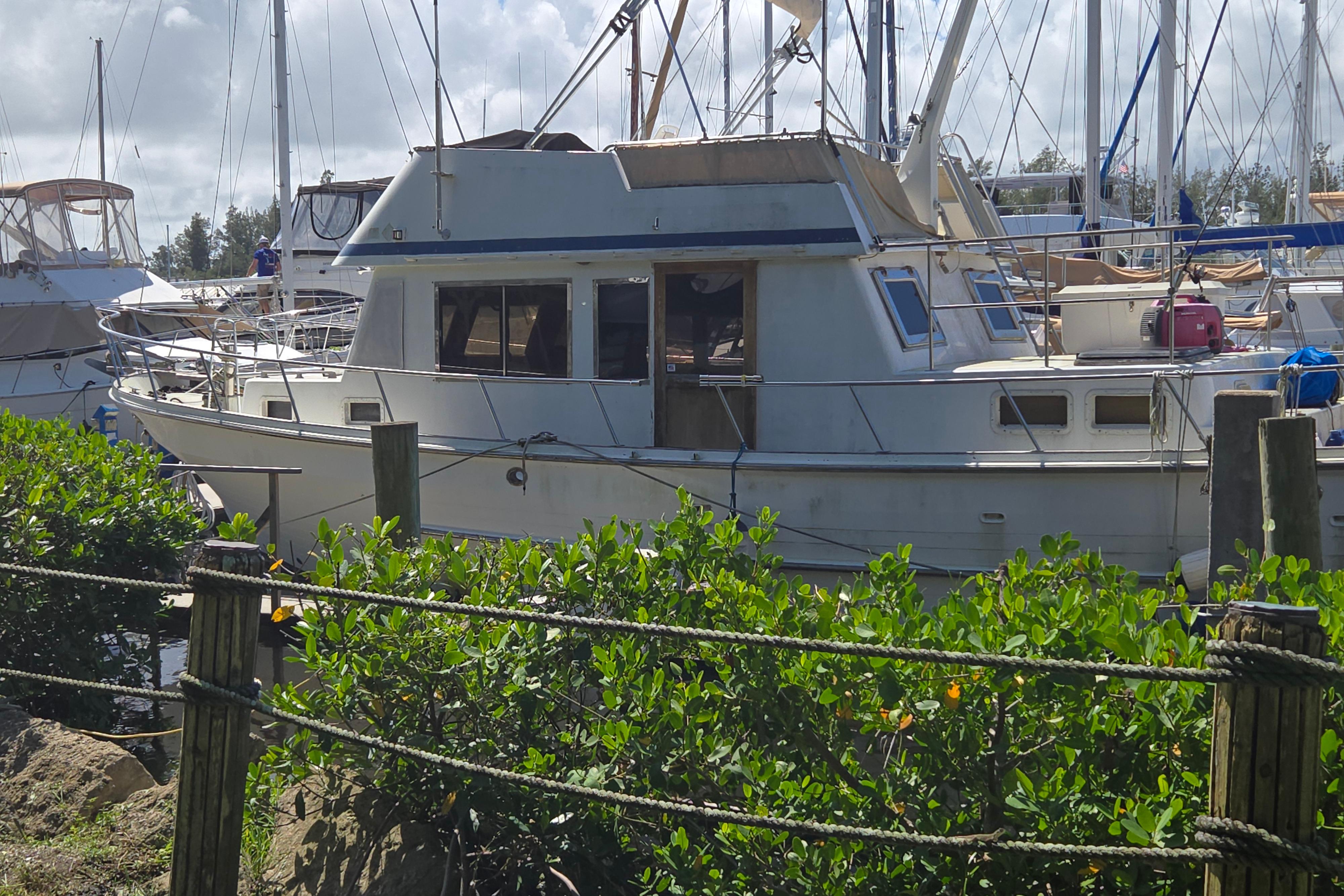 1983 Custom Present 38 Double Cabin Trawler docked at marina, surrounded by greenery.