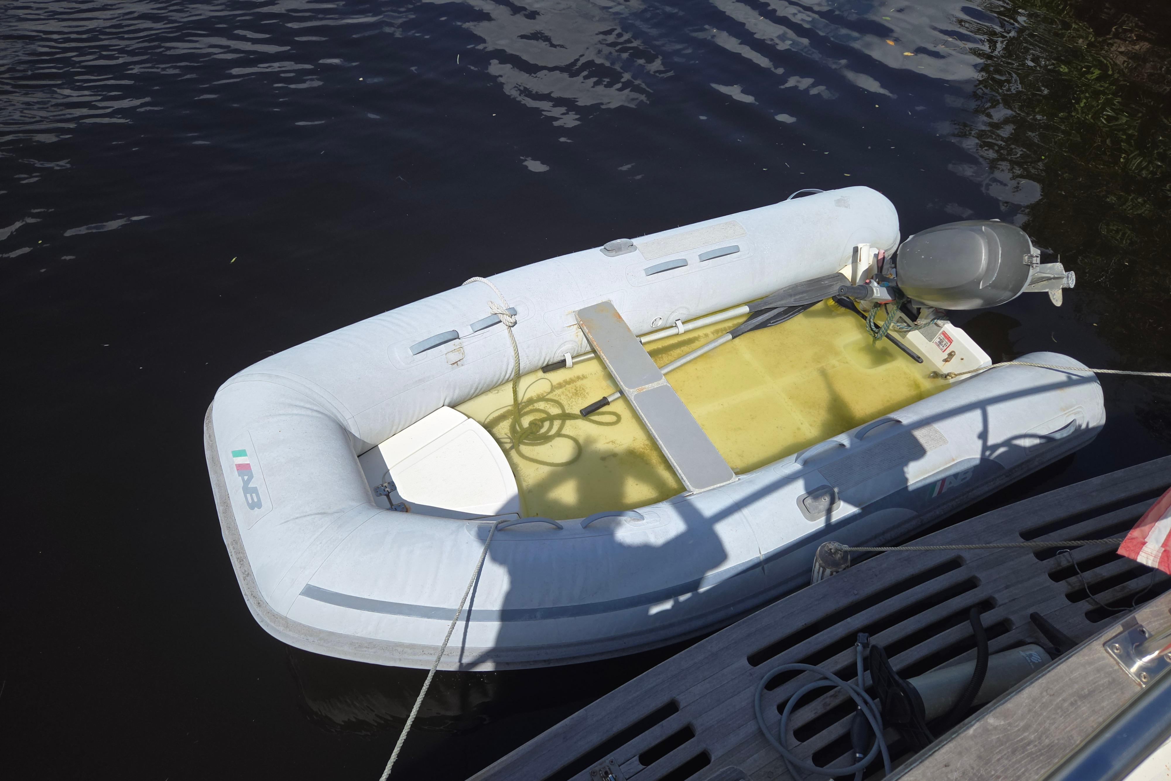 Inflatable dinghy with outboard motor beside 1983 Custom Present 38 Double Cabin Trawler.