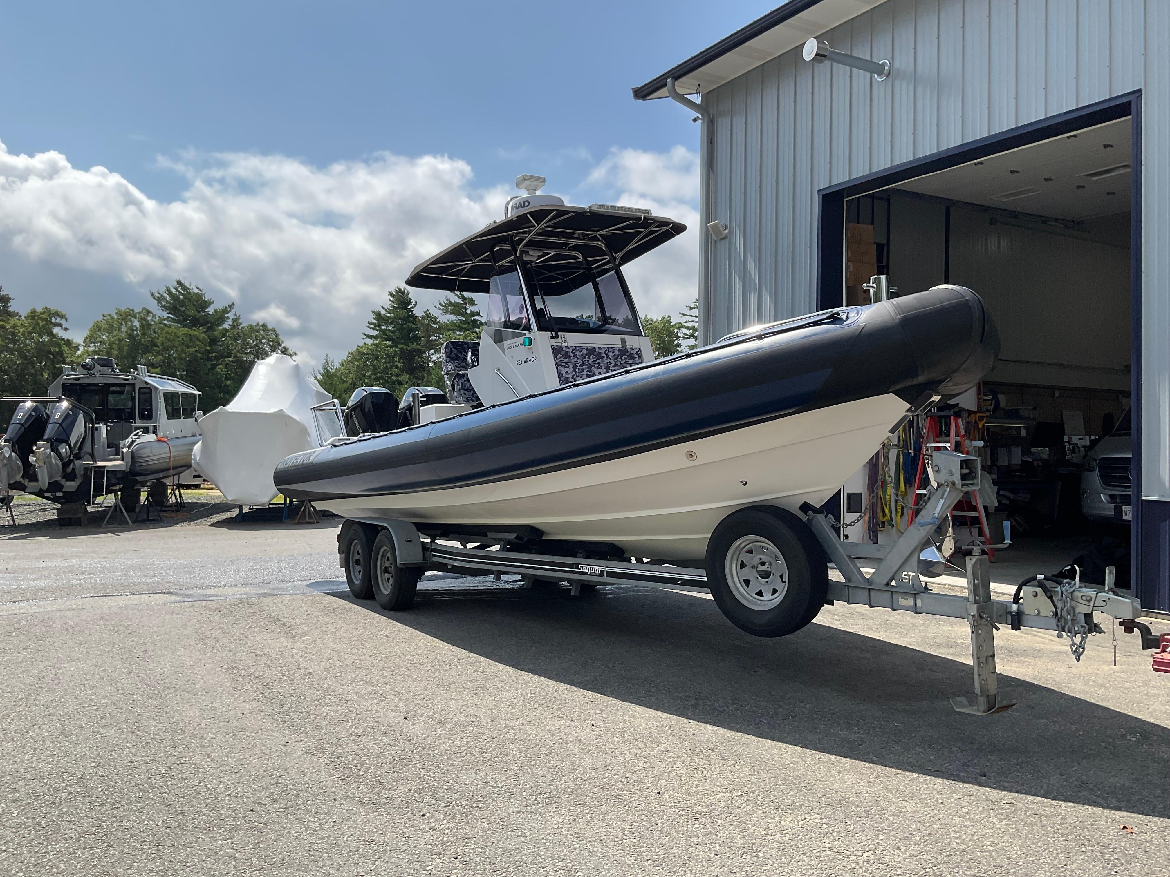 2019 Protector 310 Chase boat on trailer outside a garage, under a partly cloudy sky.