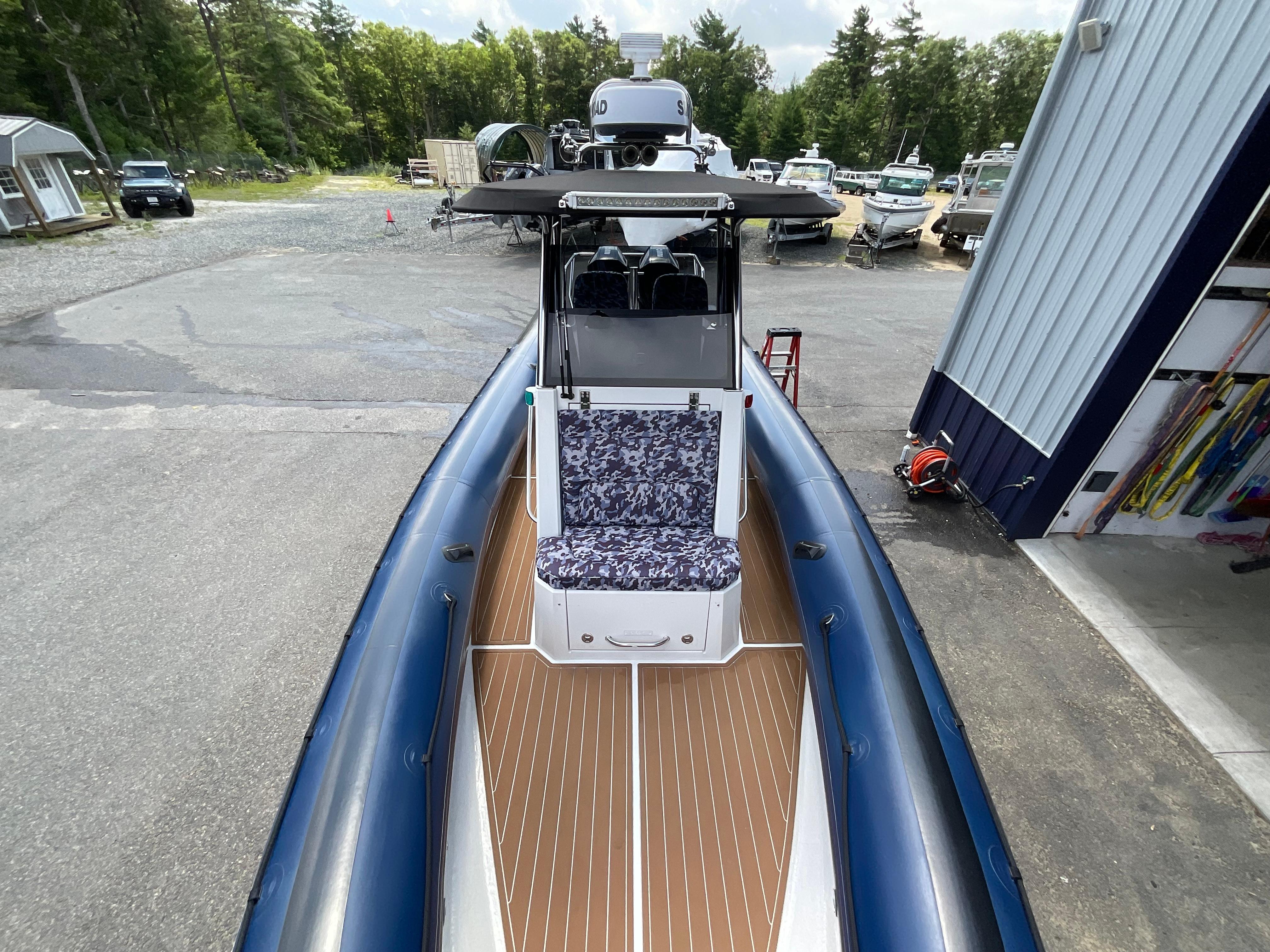 2019 Protector 310 Chase boat with blue inflatable sides and patterned seating, docked outdoors.