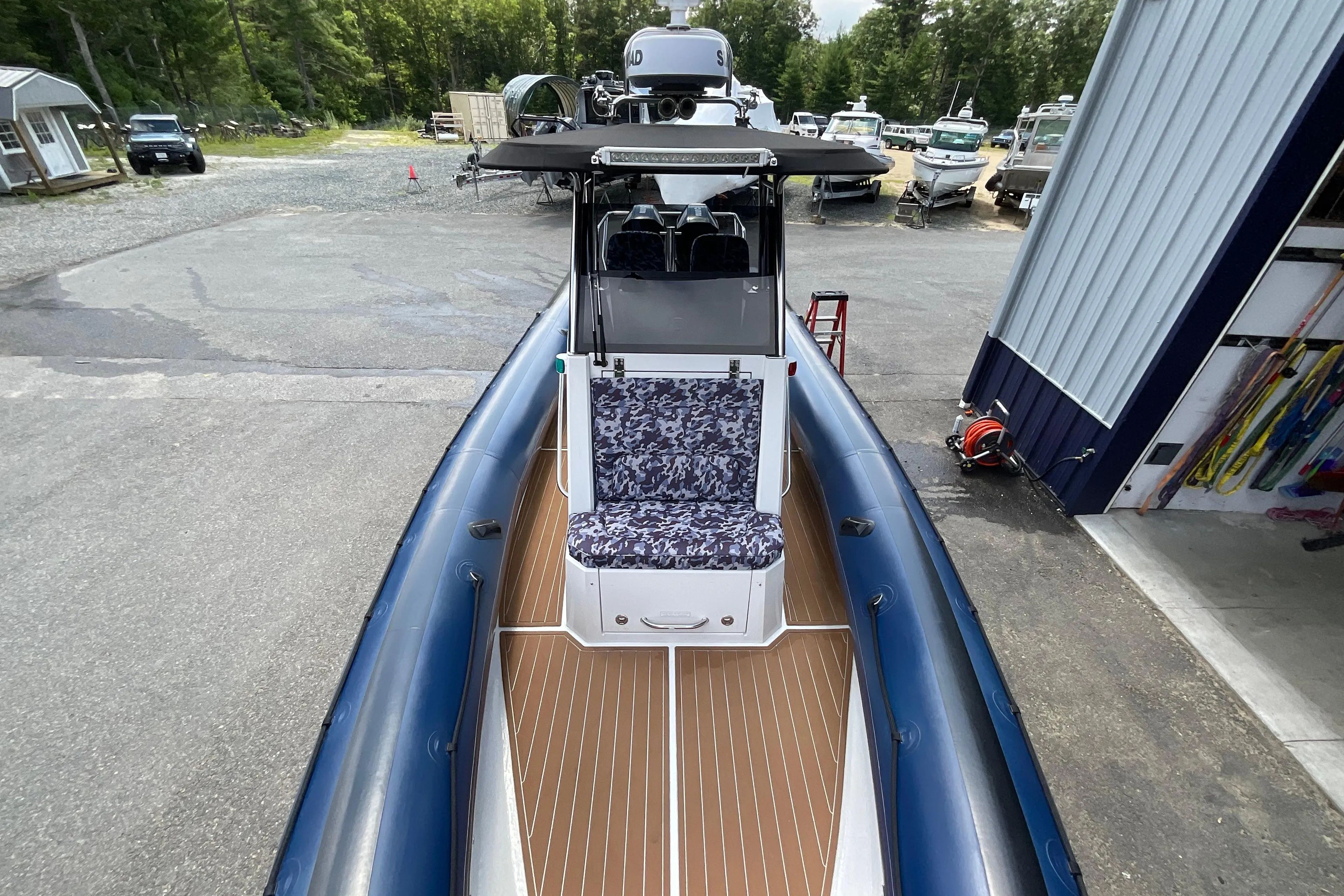 2019 Protector 310 Chase boat with blue inflatable sides and patterned seating, docked outdoors.