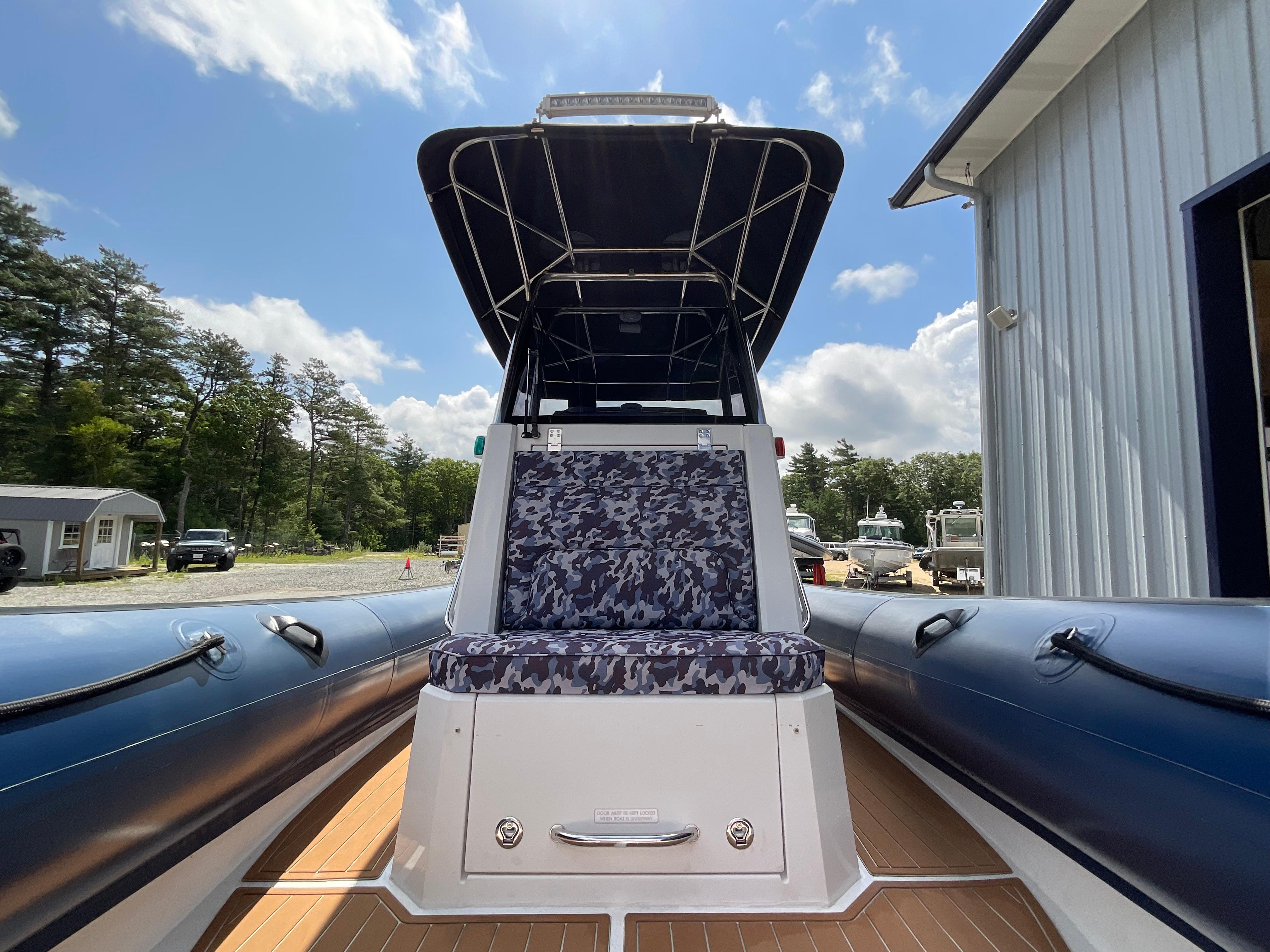2019 Protector 310 Chase boat with camo seating, docked near a building under a blue sky.